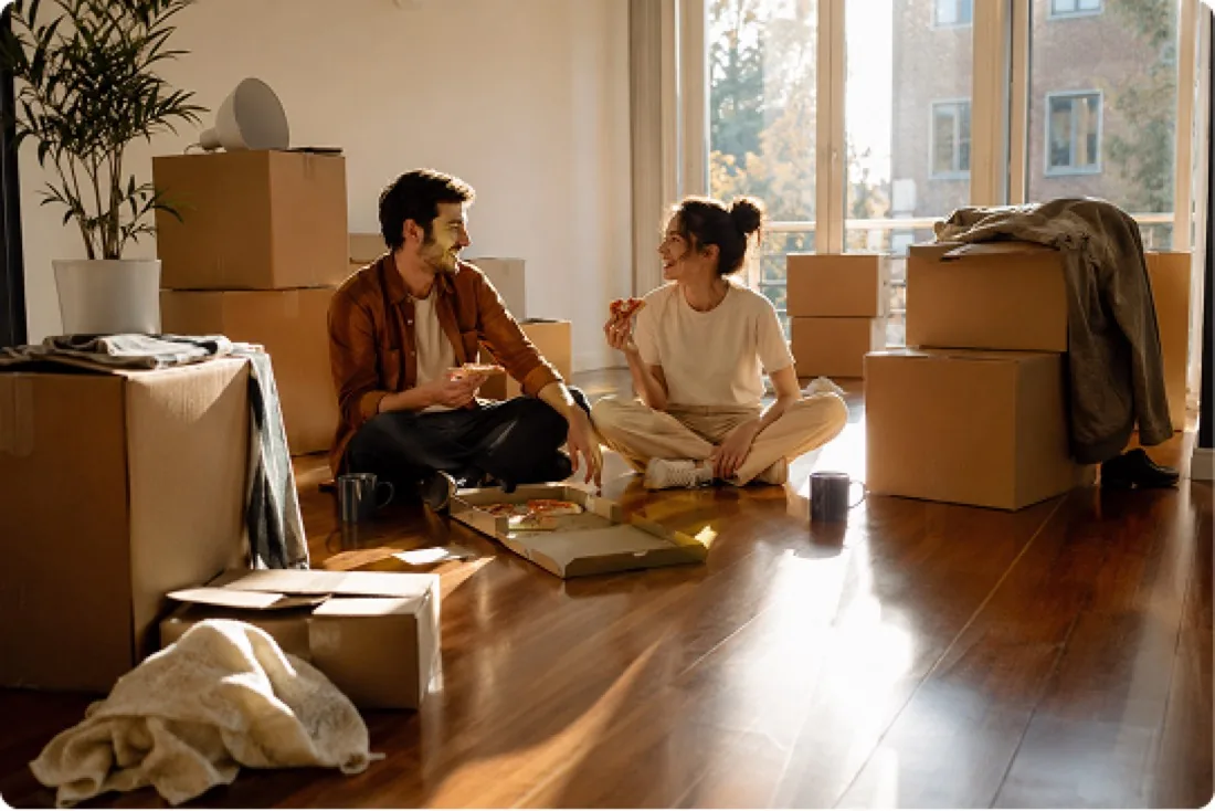 A couple sharing pizza on the floor of their new home on moving day